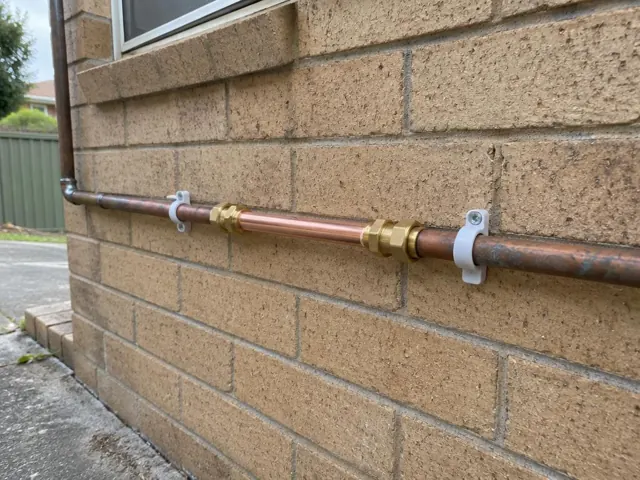 Repaired copper water pipe on a brick exterior wall in Eastlakes